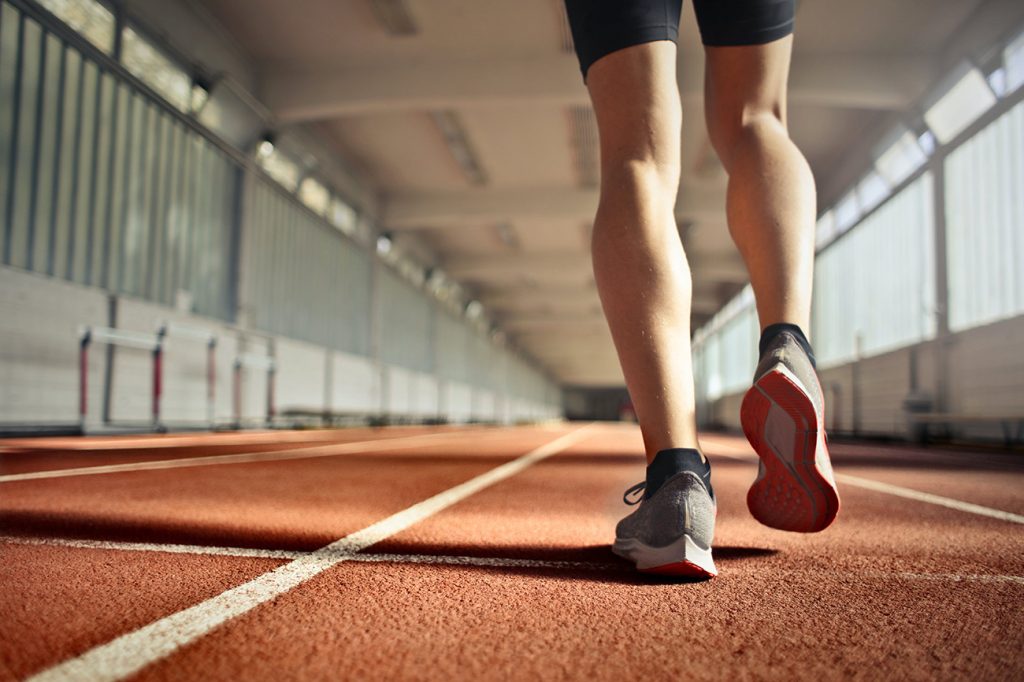 Close-up of a person running on an indoor track.